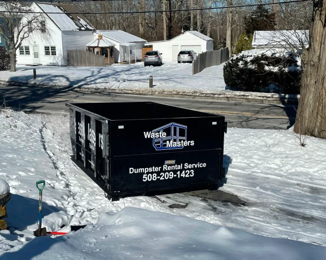 black dumpster in the middle of a patio covered in snow